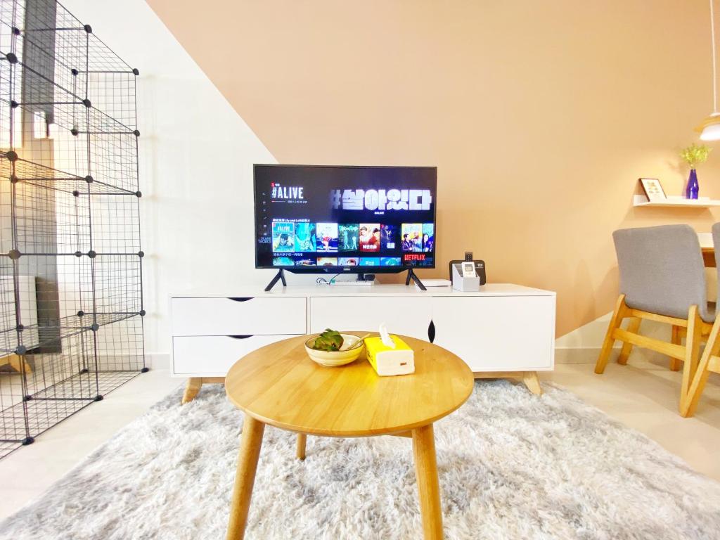 ein Wohnzimmer mit einem Tisch und einem TV in der Unterkunft Lily and Loft - Queensville @ Kuala Lumpur - Netflix in Kuala Lumpur