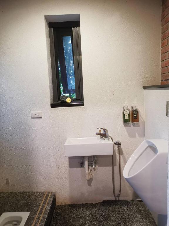 a bathroom with a sink and a urinal and a window at 建築師湧泉泡湯會館 in Dongshan