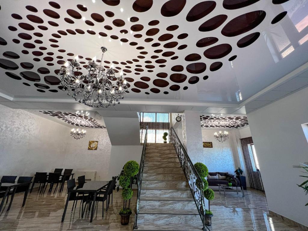 une salle à manger avec un plafond orné d'un lustre dans l'établissement Motel Infinit, à Târgu Jiu