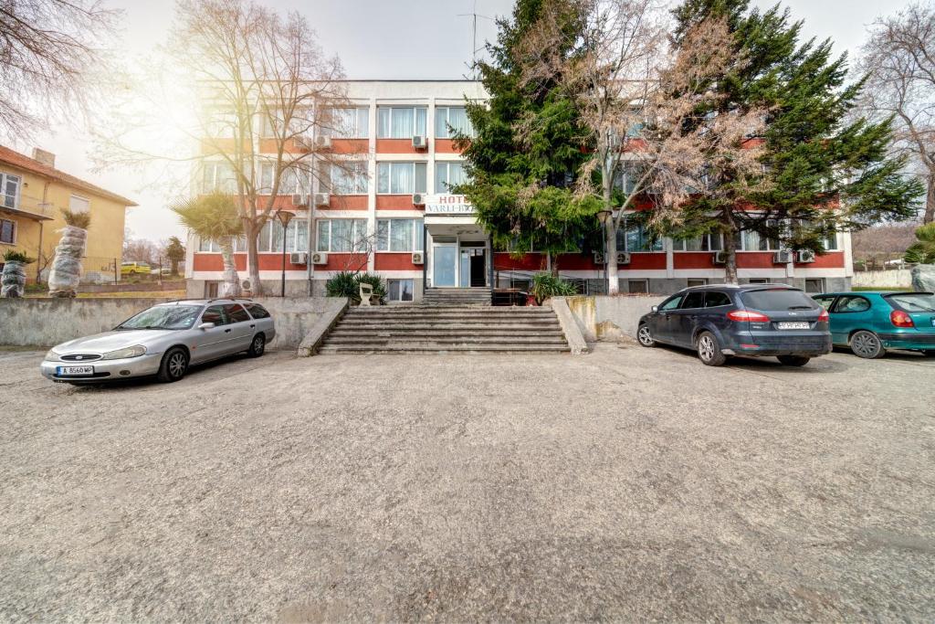 dos autos estacionados en un estacionamiento frente a un edificio en Hotel Varly Bryag en Burgas