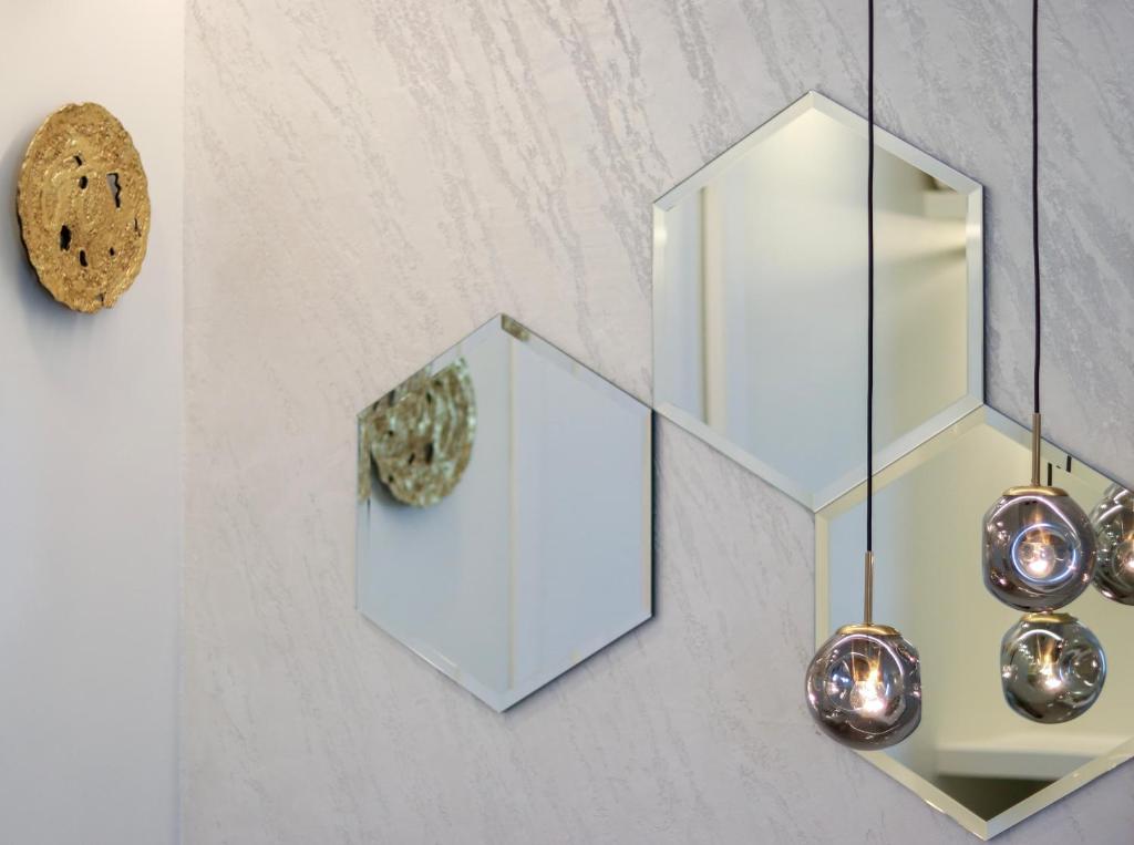 a wall with two mirrors and a clock at Double A Luxury Room in Olbia