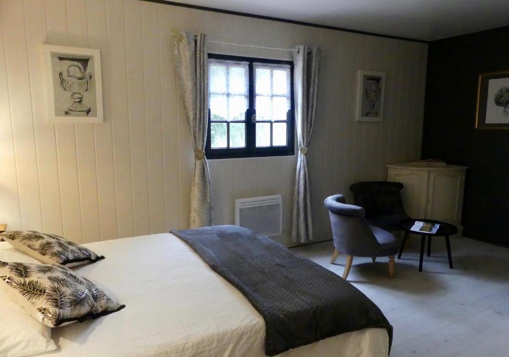 a bedroom with a bed and a window and a chair at La petite auberge in Villefranche-du-Périgord