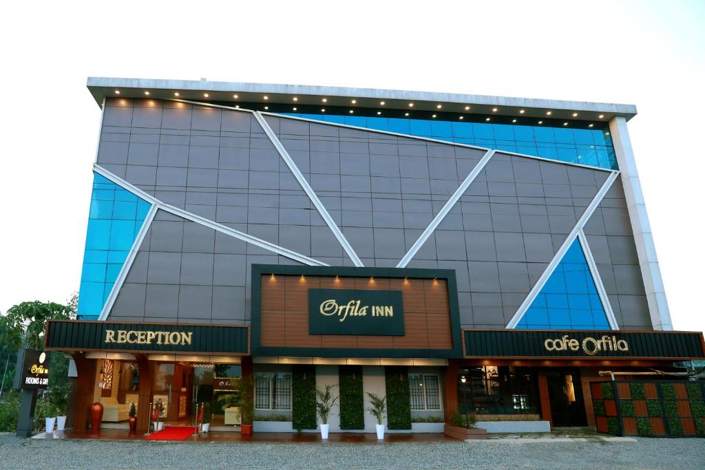 a large glass building with lights on it at ORFILA INN Airport Hotel in Angamaly