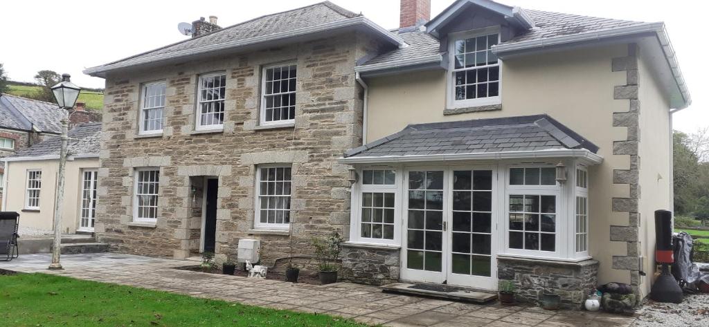 a stone house with white windows and a driveway at Penbetha House B&B in Truro