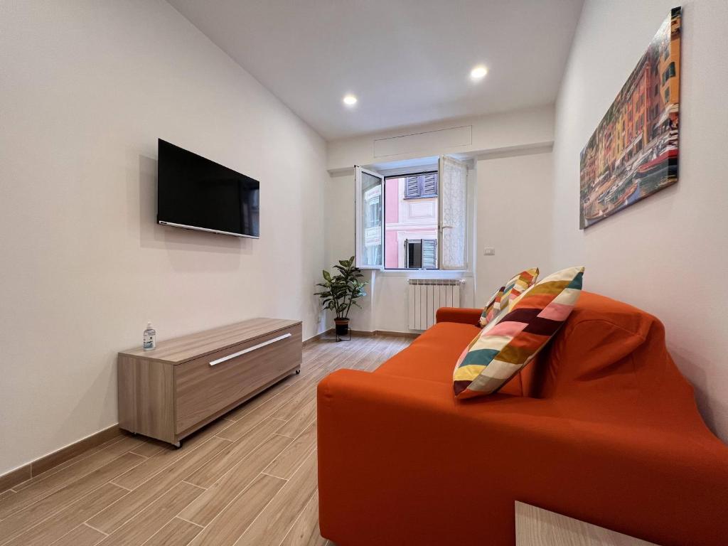 sala de estar con sofá naranja y TV de pantalla plana en Vico dell'amore, en Rapallo