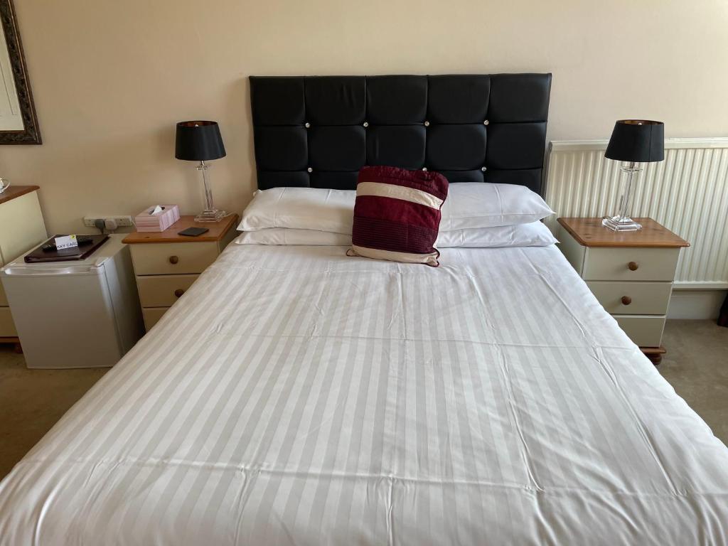 uma grande cama branca com uma almofada vermelha em Diamonds Lodge near York Hospital em York