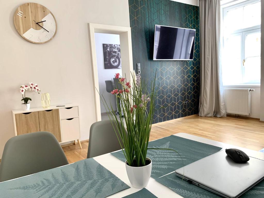 un tavolo con un portatile e un vaso con dei fiori sopra di Premium Apartment am Einsiedlerpark a Vienna