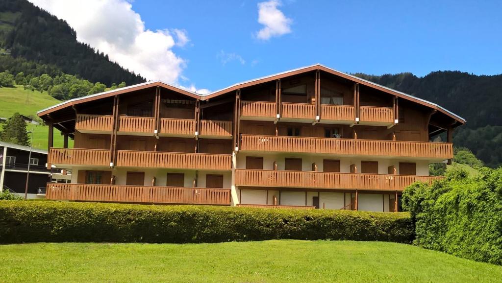 un gran edificio con balcones de madera en la parte superior de un campo en APPARTEMENT PRAZ VILLAGE en Praz-sur-Arly