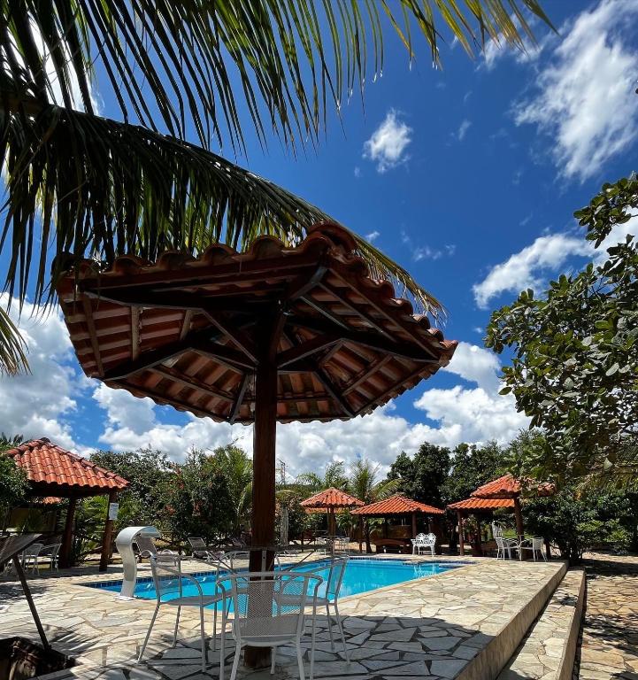um guarda-sol e cadeiras junto a uma piscina em Pousada Encanto dos Anjos em Pirenópolis