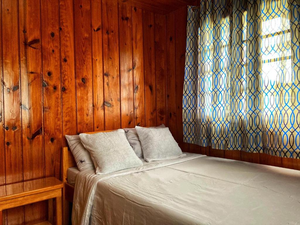 a bedroom with a bed with wooden walls and a window at Dagdag Village Homestay - Sagada in Sagada