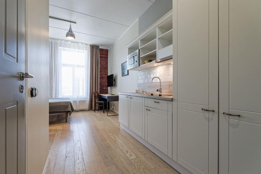 een keuken met witte kasten, een wastafel en een bureau bij Stylish City Center Studio Apartment in Tallinn