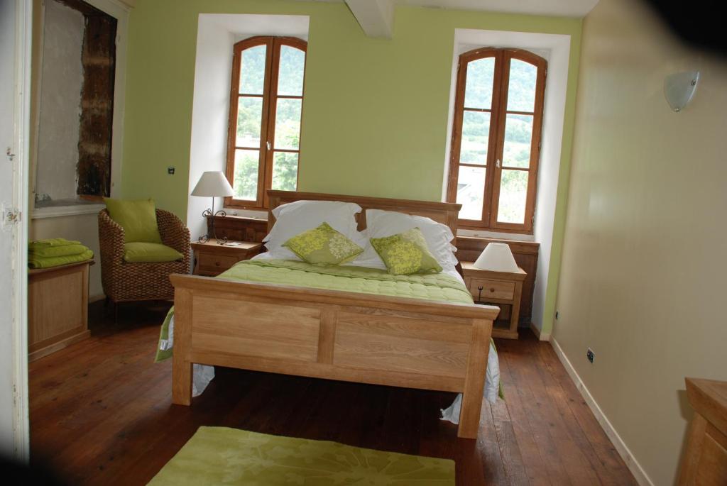 a bedroom with a bed with green sheets and two windows at La Petite Maison des Montagnes in Luz-Saint-Sauveur