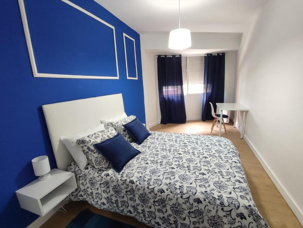 een blauwe slaapkamer met een bed en een blauwe muur bij APARTAMENTO RECIEN REFORMADO EN EL CENTRO DE VILAGARCÍA DE AROUSA. in Vilagarcia de Arousa
