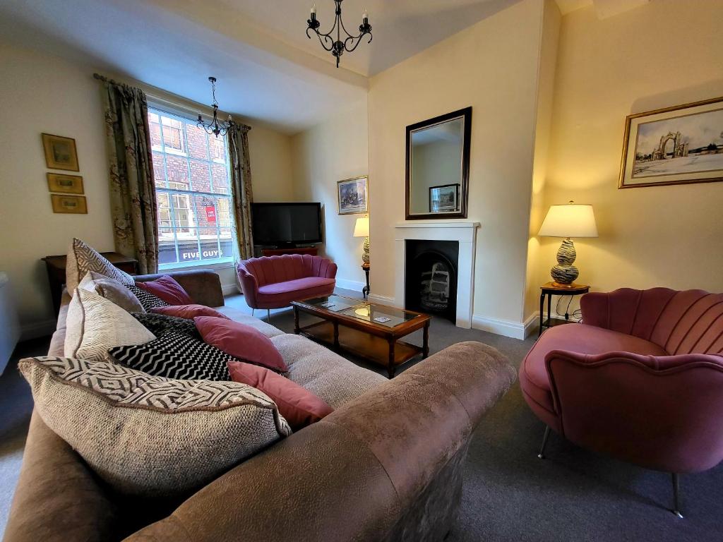 uma sala de estar com um sofá e cadeiras e uma lareira em 50a Low Petergate em York