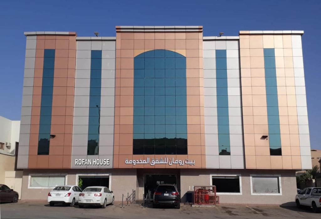 een groot gebouw met auto's geparkeerd op een parkeerplaats bij Rofan house serviced apartments in Riyad