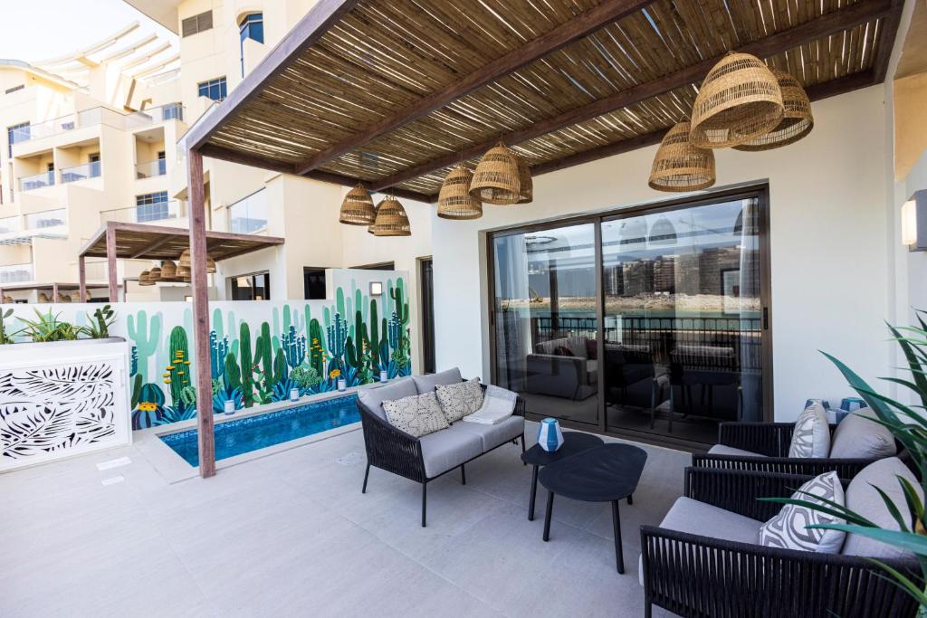 a patio with a couch and chairs and a pool at The Townhouses The Pearl in Doha