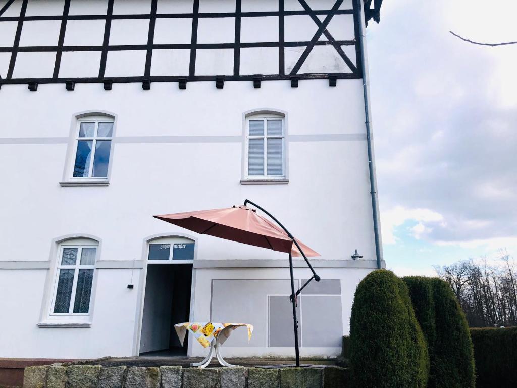 une maison blanche avec un parasol devant elle dans l'établissement Ferienhof - Ferienwohnung, à Gadebusch