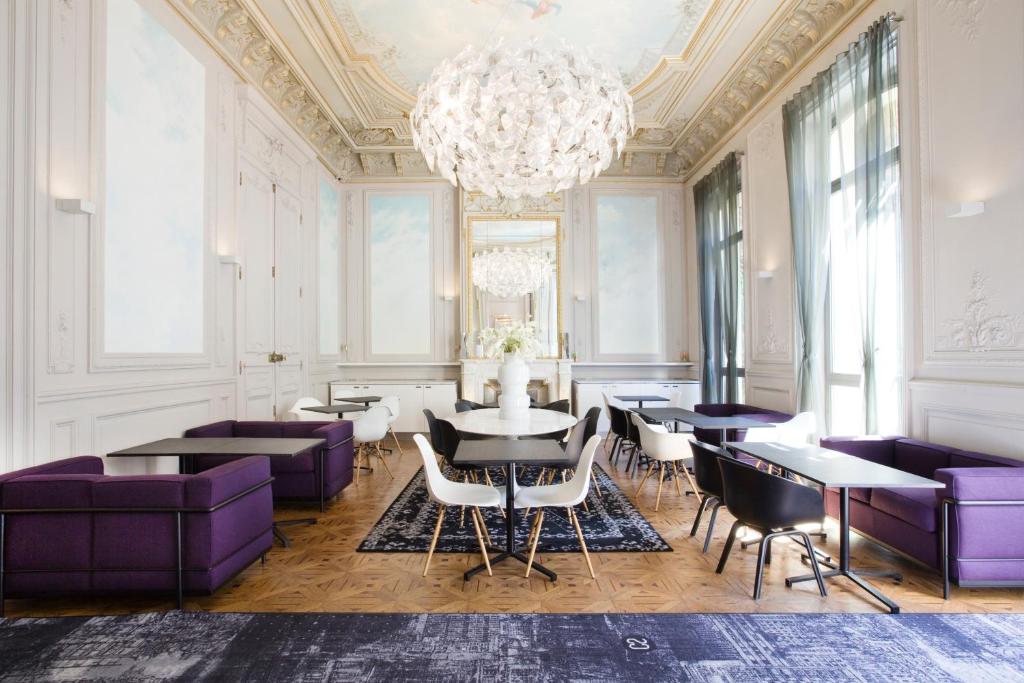 a dining room with purple furniture and a chandelier at Hotel C2 in Marseille