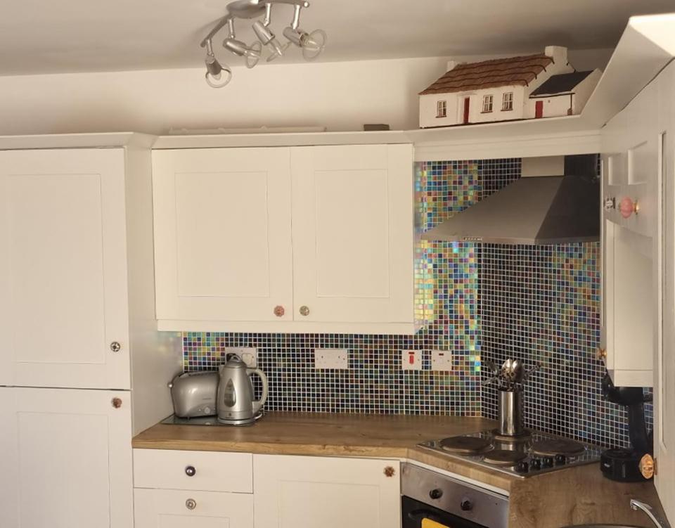 a kitchen with white cabinets and a counter top at Be's Cottage in Malin Head