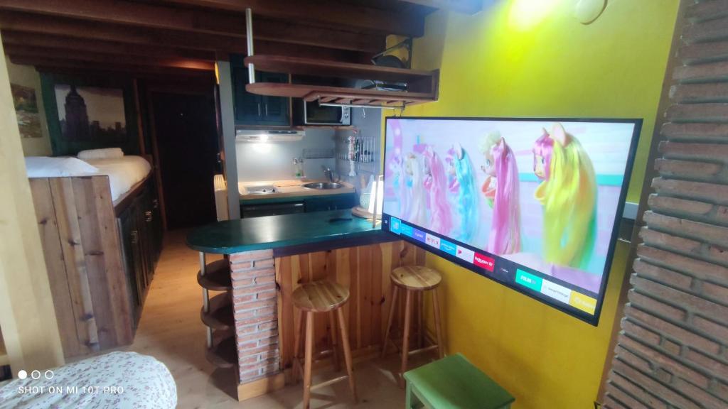 einen Schreibtisch mit einem großen Monitor an der Wand in der Unterkunft Presidente Deluxe in Sierra Nevada