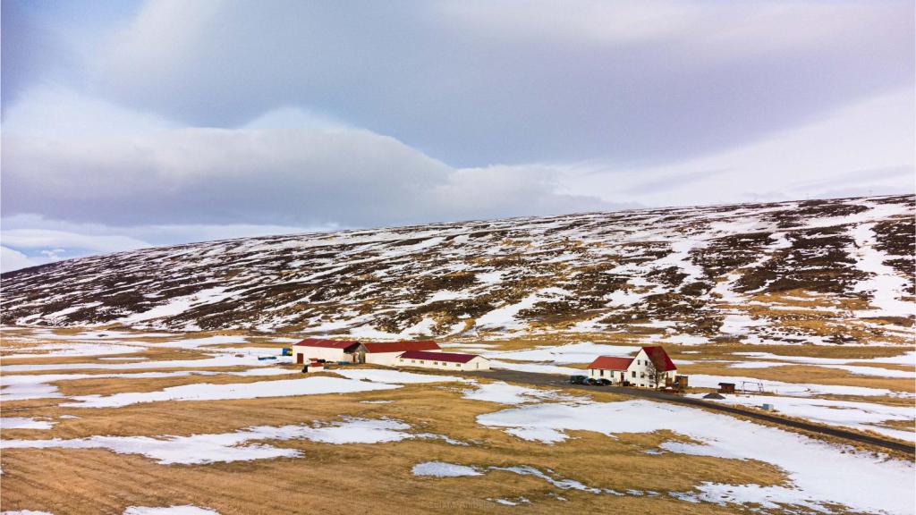 a farm on a snow covered hill with houses at Fljótsbakki Hotel in Godafoss