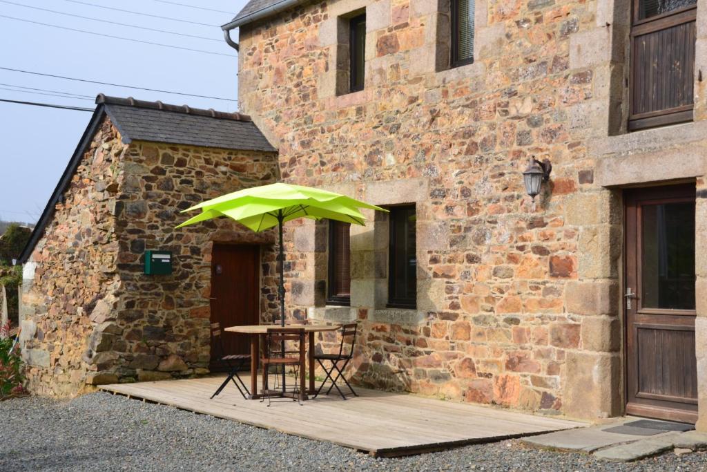 a table with a green umbrella next to a building at Gite Gloria in Lannion