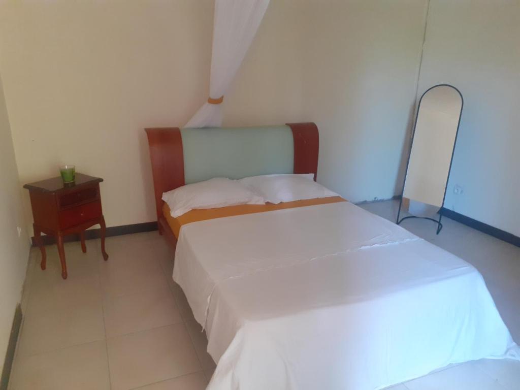 two beds in a small room with a night stand and a bed at Bois joli village in Le Marin