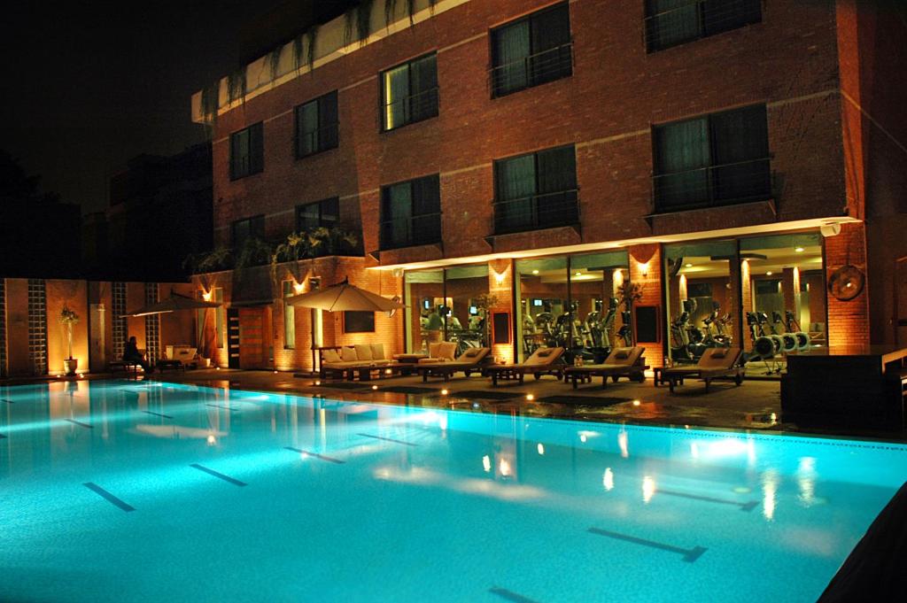 a large swimming pool in front of a building at night at The Residency Hotel in Lahore