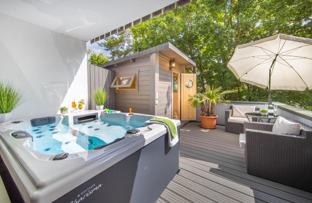 a hot tub on a deck with an umbrella at Hotel Am Kurpark Späth in Bad Windsheim