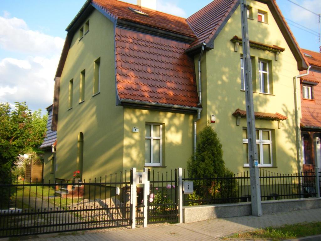una casa amarilla y verde con una valla metálica en Apartament Tina, en Dzierżoniów