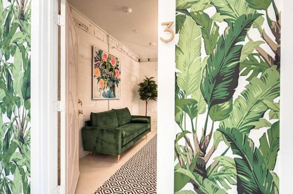 a green couch in a room with a mural of leaves at The Oleander Hotel Room Number 3 in Galveston