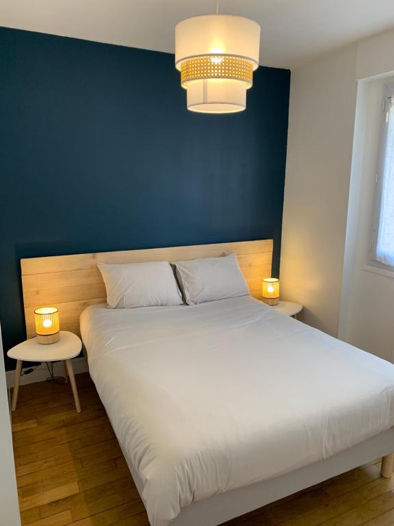 ein Schlafzimmer mit einem großen weißen Bett mit zwei Tischen in der Unterkunft Honoriane - Appartements meublés in Gien