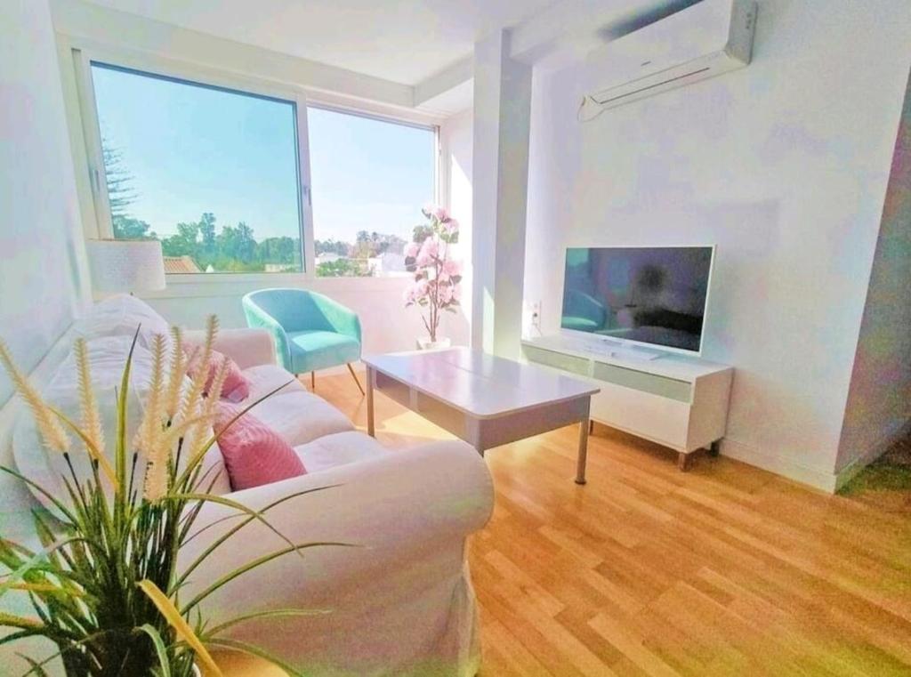 uma sala de estar com um sofá branco e uma televisão em Plaza de España. Dreams em Sevilha