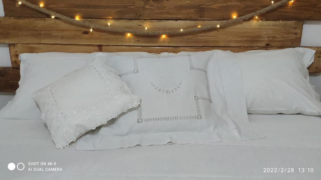 - un lit avec des oreillers blancs et une chaîne de lumières dans l'établissement Kryptàdion, à Grottaglie