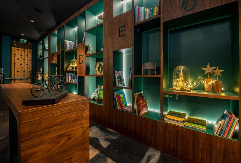 a library with green walls and wooden shelves with books at Hôtel Tandem - Boutique Hôtel in Strasbourg