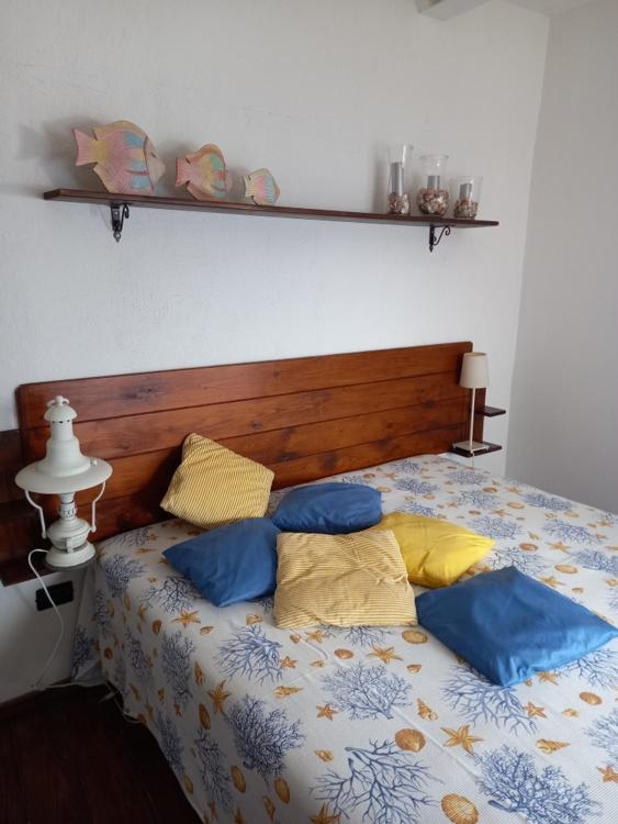 a bed with blue and yellow pillows on it at Sole e mare in San Felice Circeo