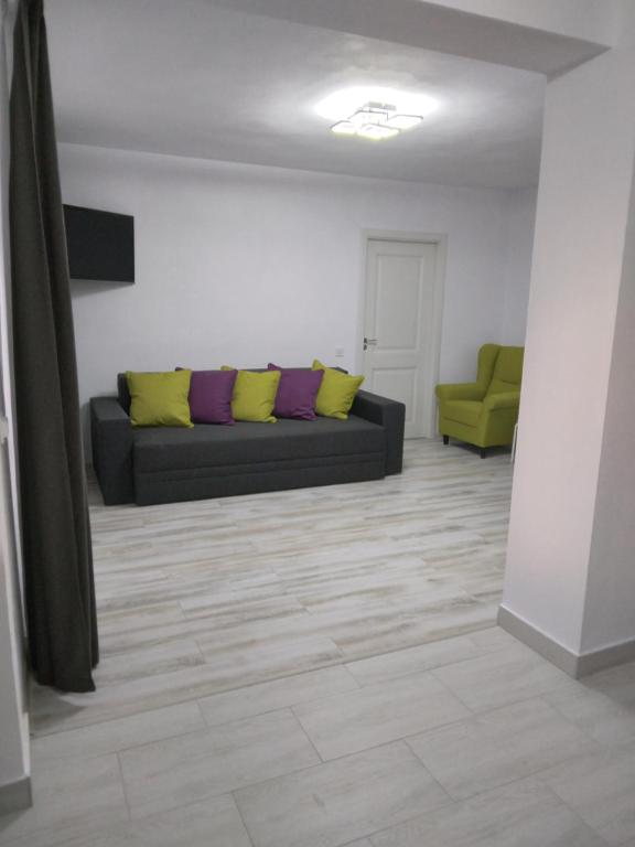 un soggiorno con divano e cuscini gialli e viola di Luxury apartament a Curtea de Argeş