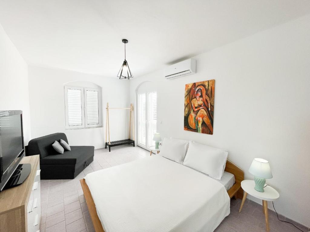 a white bedroom with a white bed and a couch at Sea View Apartment Amaro in Korčula