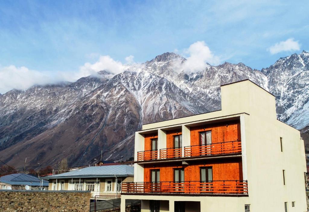 un bâtiment avec des montagnes enneigées en arrière-plan dans l'établissement Eltisy Guest House, à Kazbegi