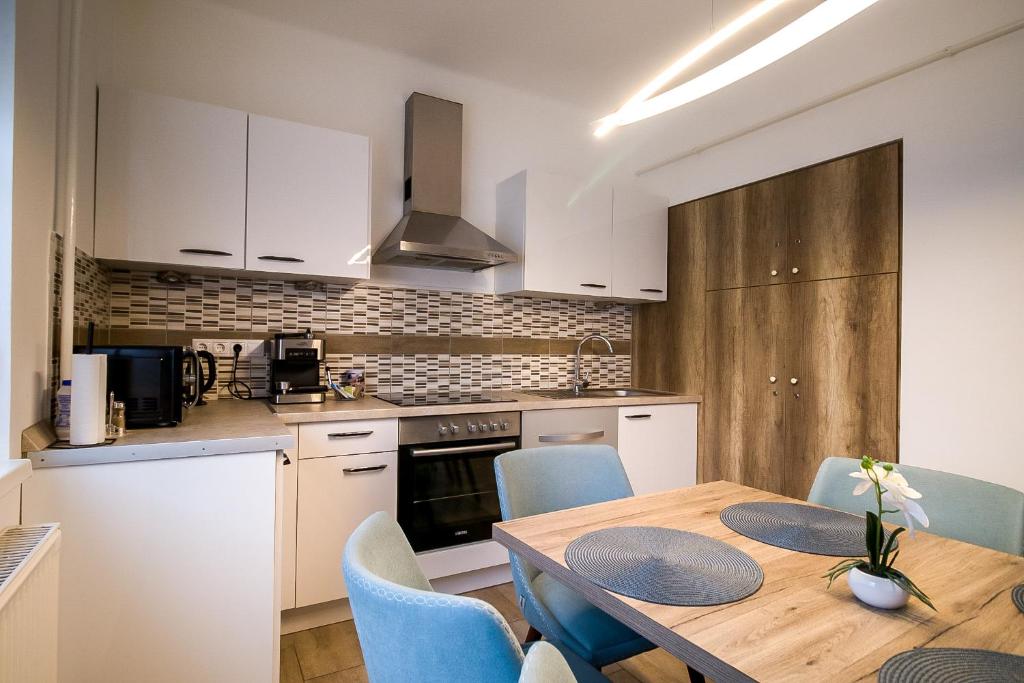 a kitchen and dining room with a wooden table and chairs at Thermal Next I Weninger Apartman Kiskunhalas in Kiskunhalas