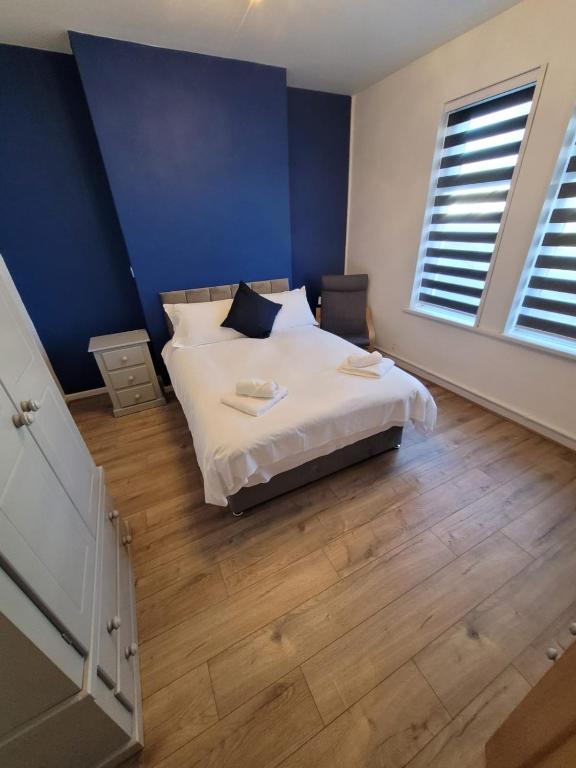 ein Schlafzimmer mit einem weißen Bett und einer blauen Wand in der Unterkunft Courtybella Mews in Newport