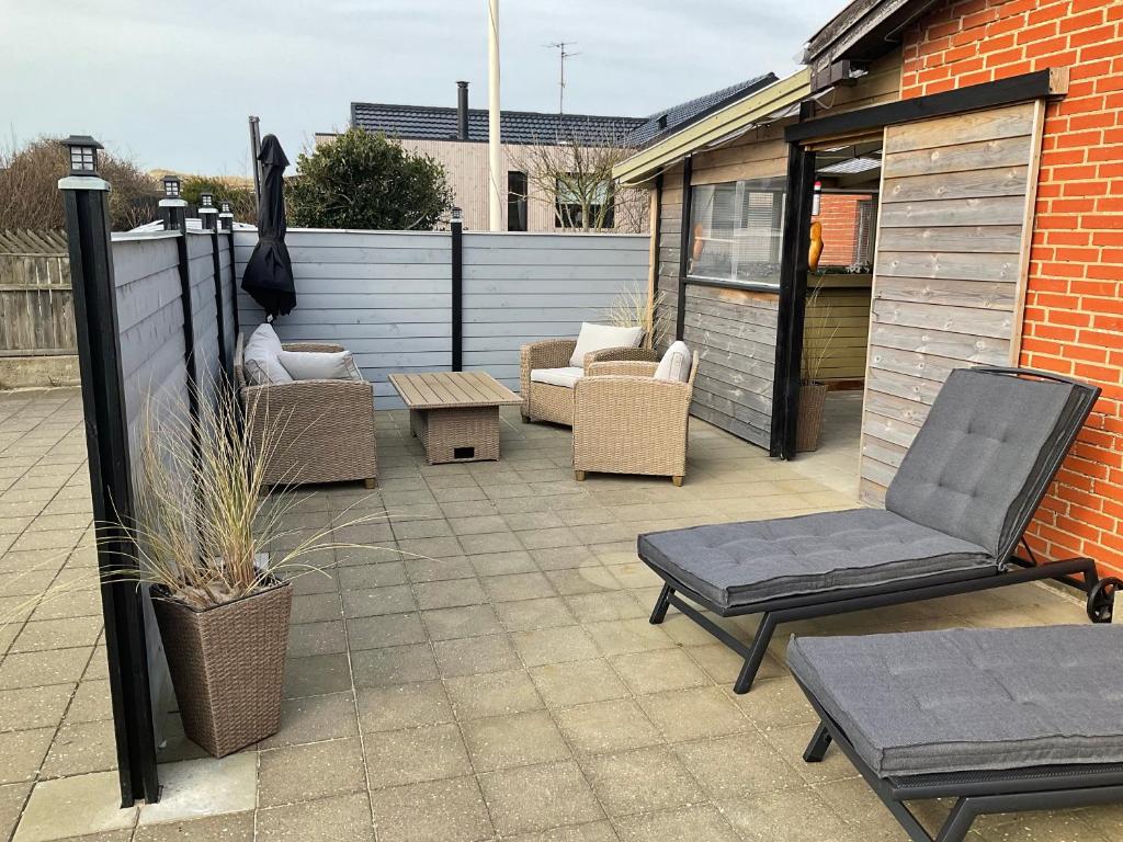 une terrasse avec des chaises, une table et un parasol dans l'établissement Strandhytten, à Hvide Sande