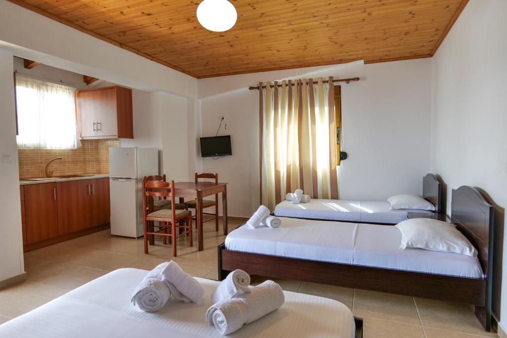 a bedroom with two beds and a kitchen with a table at Villa Abedini in Ksamil