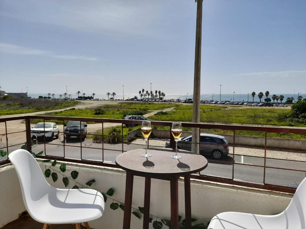 - une table avec deux verres de vin sur le balcon dans l'établissement Carcavelos Surf Beach House, à Carcavelos