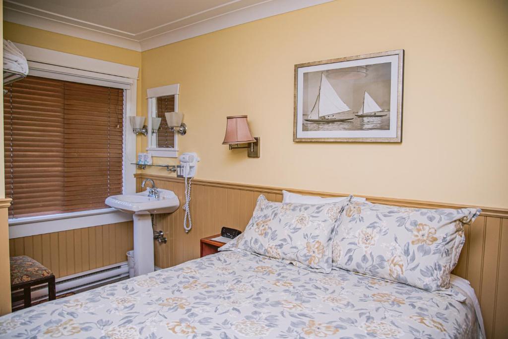 a bedroom with a bed and a sink and a window at Salt Spring Inn in Ganges