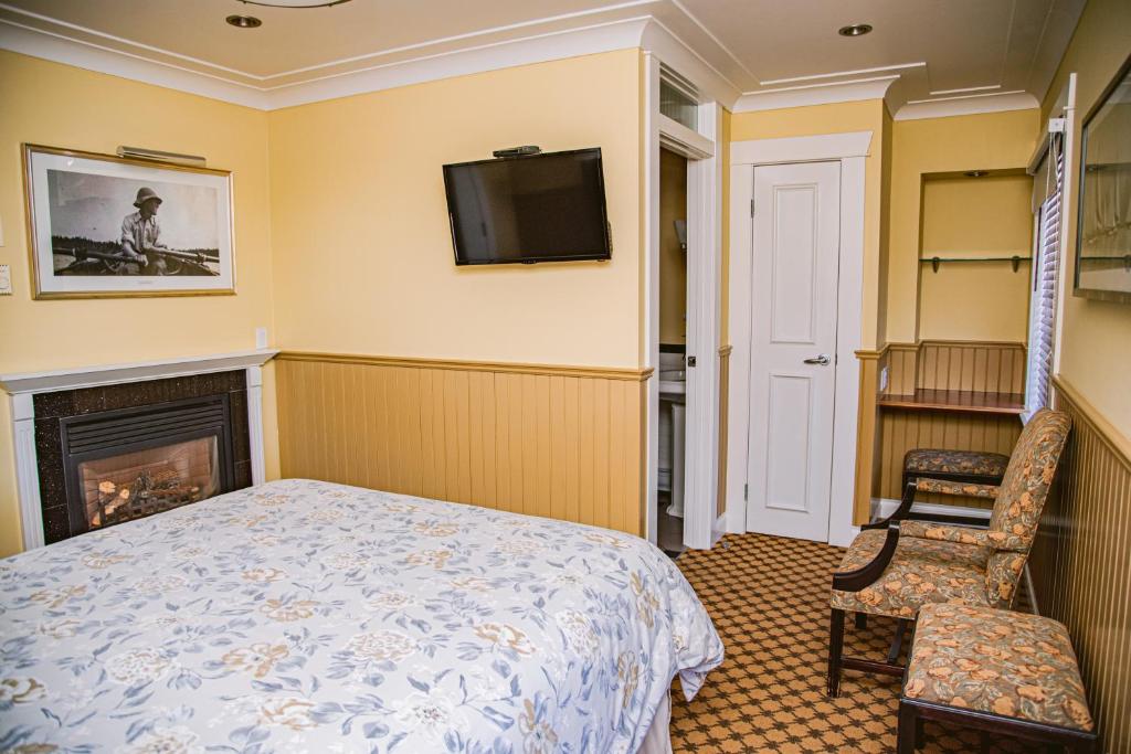a bedroom with a bed and a tv and a fireplace at Salt Spring Inn in Ganges