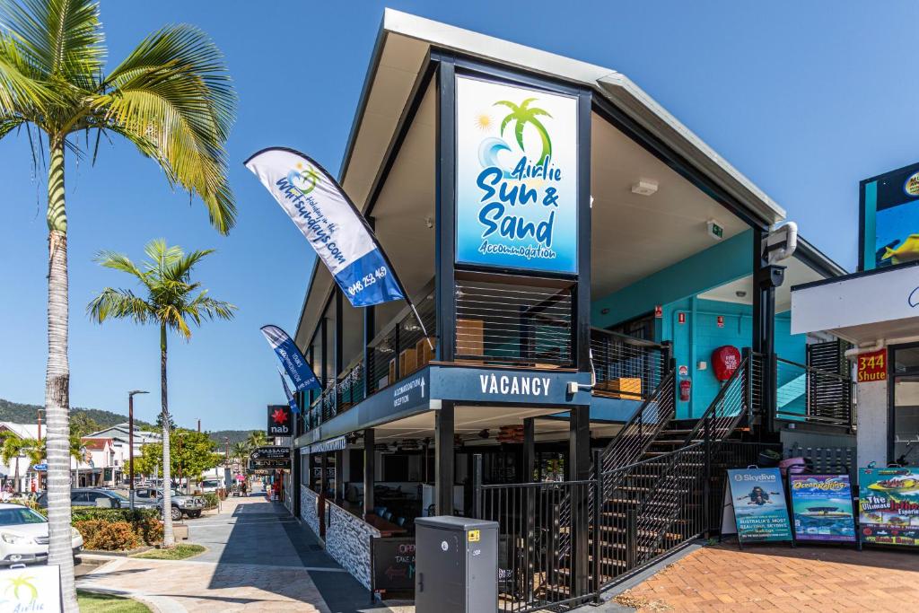 a store on a street with a palm tree at Airlie Sun & Sand Accommodation #3 in Airlie Beach
