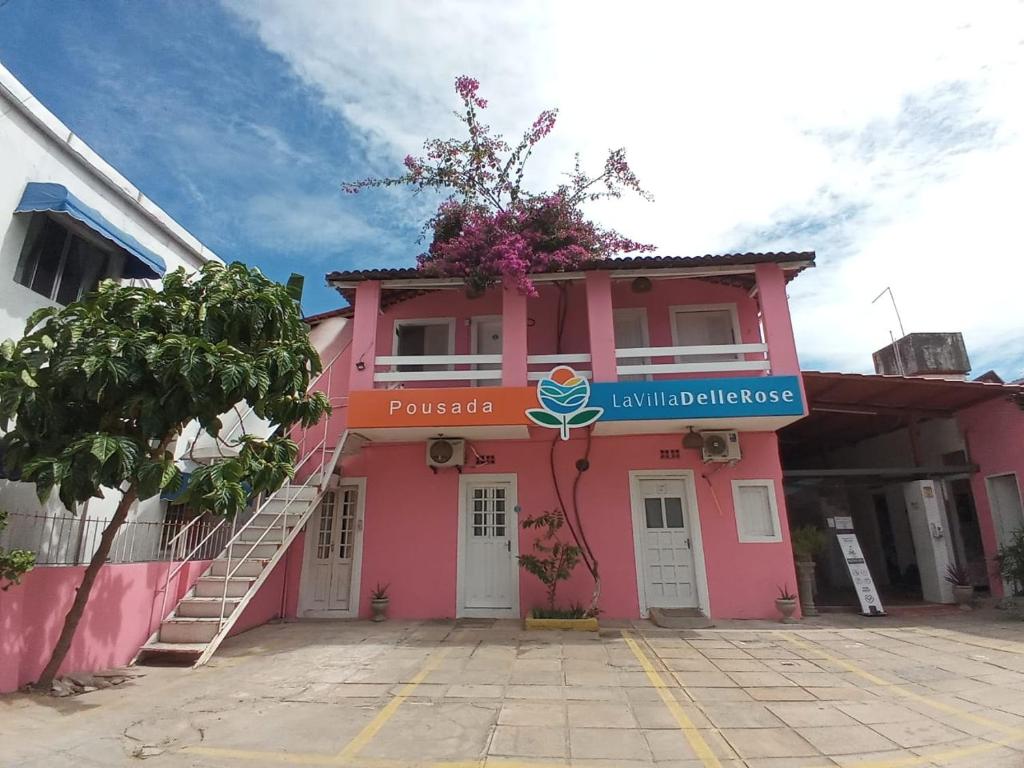 un edificio rosa con un cartel. en Pousada Delle Rose, en Porto de Galinhas