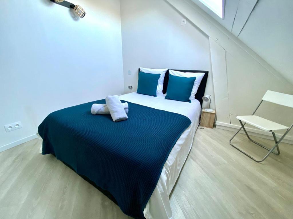 - une chambre avec un lit doté d'oreillers bleus et d'une chaise dans l'établissement Appartement vue sur les étoiles, à Charleville-Mézières