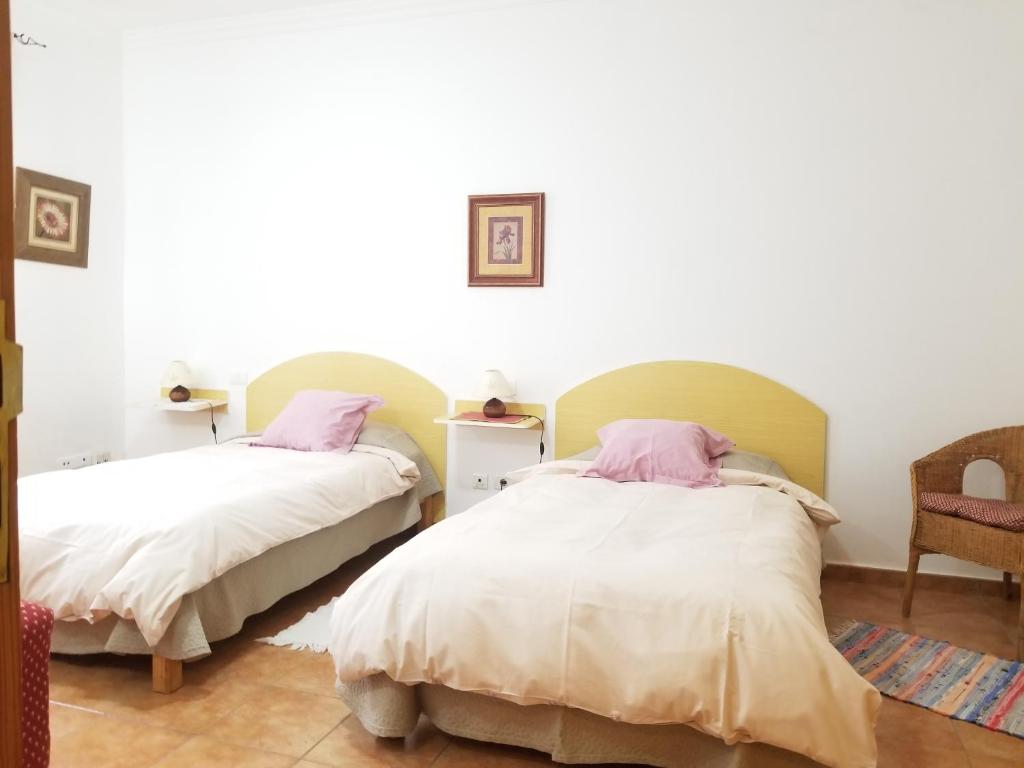 a bedroom with two beds and a chair at Casa Camino Tamadaba II (bottom home） in Agaete